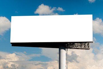 Wall Mural - blank wide horizontal white billboard or large display against blue sky with white clouds - mock up.