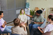 canvas print picture Group of teenagers sitting on chairs and talking their problems to psychologist who listening to them and giving advice during psychology therapy group