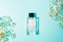 Perfume Bottle On Light Blue Background With Gypsophila Flowers. Beauty, Fashion Concept. Top View, Flat Lay