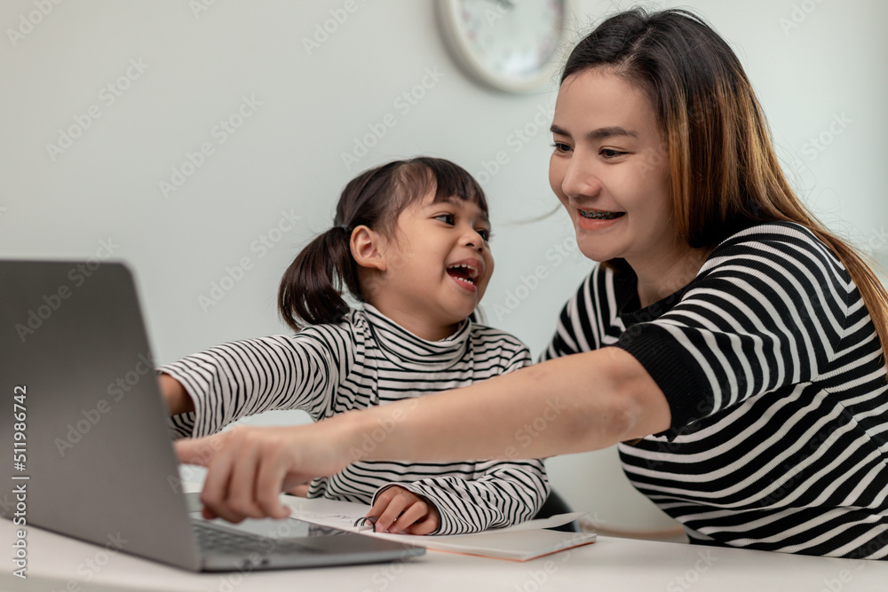 Asian little young girl kid learning online class at home with mother ...