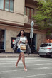 © Kostiantyn - Attractive young stylish woman walking the street and crossing road with smartphone in hands.