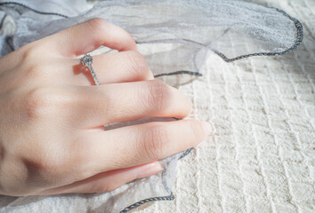 Wall Mural - Close up of diamond ring on woman finger with sunlight and shadow background. Love, valentine, relationship and wedding concept. Soft and selective focus.