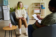 © Seventyfour - Teenage girl with trendy hairstyle sitting on armchair and discussing her problems with school counselor at office
