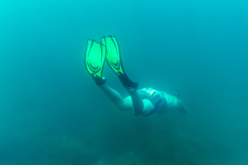 Wall Mural - A freediver dives into the depths with his fins