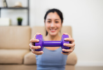 Wall Mural - Attractive asian young fitness woman lifting dumbbell weights workout at home in living room. Fresh feeling female training and exercise wearing sport wear fit body.