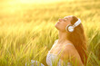 © Antonioguillem - Woman meditating listening to music at sunset in a field