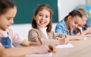 Wall Mural - Cheerful girl solving test with classmates