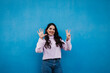 © Westend61 - Smiling young beautiful woman showing number 8 in front of blue wall