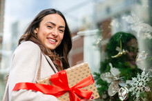 Happy Woman With Christmas Present Standing By Glass Window