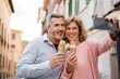 © Westend61 - Smiling couple with ice cream taking selfie on mobile phone in city
