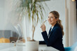 © Westend61 - Smiling businesswoman holding eyeglasses sitting at desk in office