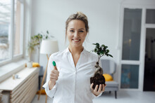Happy Businesswoman Holding Plant Showing Green Thumb In Office