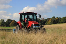 Red Tractor Cutting Grass At A Golf Course In Autumn
