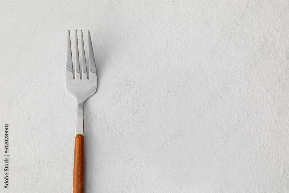 Stylish stainless steel fork on light background, closeup