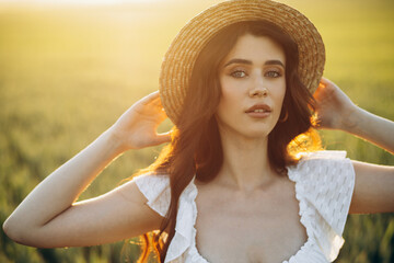 Beautiful woman in the field wearing white dress and hat