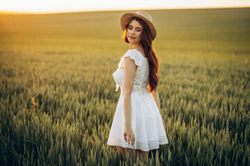 Beautiful woman in the field wearing white dress and hat