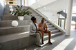 © Westend61 - Businessman and businesswoman sitting on stair discussing in modern office