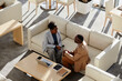 © Westend61 - Young businesswoman discussing plan with colleague sitting on sofa in modern office