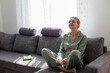 © Westend61 - Relaxed mature woman sitting on couch in living room with closed eyes