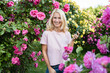 © Westend61 - Happy woman holding mobile phone amidst rose garden