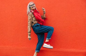 Active senior woman dancing against a red background