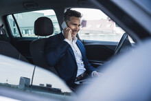 Happy Businessman Talking On Smart Phone Sitting On Driver's Seat In Car