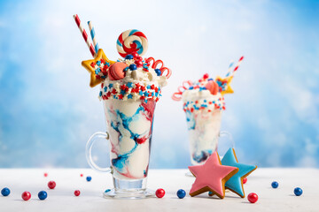 Crazy milk shake with ice cream,whipped cream, marshmallow,cookies and colored candy in glass. Sweet dessert for Fourth of July. Idea milkshake for Patriotic day.