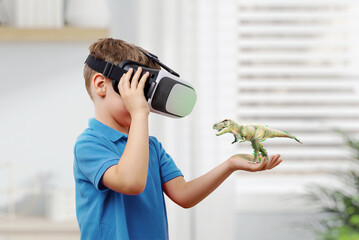 Wall Mural - boy with vr glasses projects a dinosaur on his arm. the concept of using virtual reality in educatio