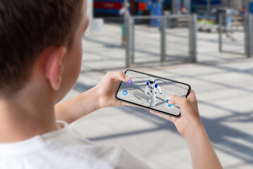 boy programs and controls the robot on the street via augmented reality technology concept