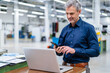 © Westend61 - Mature businessman using laptop and smartphone in factory