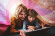 © Westend61 - Cute boy with mother using tablet PC under blanket