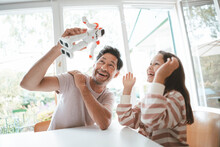 Happy Daughter And Father Playing With Toy Robot At Home