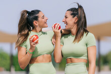Happy Young Woman With Twin Sister Holding Apple On Sunny Day