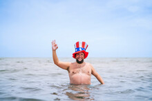 Smiling Shirtless Obese Man Wearing Uncle Sam Hat Showing OK Sign In Sea