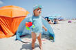 © Westend61 - Boy holding toy car standing in front of tent at beach on sunny day