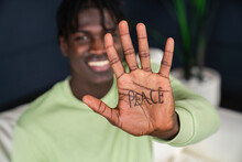Smiling Man Showing Peace Written On Palm Of Hand