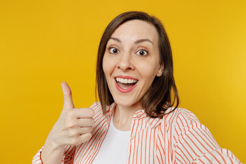 Poster - Close up young happy smiling satisfied fun woman she 30s wear striped shirt white t-shirt doing selfie shot pov on mobile cell phone show thumb up isolated on plain yellow background studio portrait.