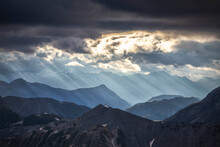 Sun Rays Filter Between Black Clouds At Sunset, Stelvio Mountain Pass, Stelvio National Park, Valtellina, Lombardy, Italy