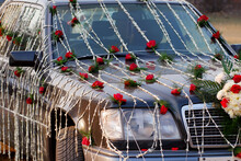 A Wedding Car Decorated With Red And White Flowers.