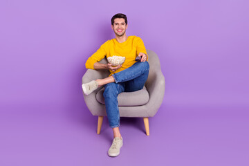 Sticker - Full length image of good mood positive man sit chair watching tv after work eat popcorn isolated on violet color background