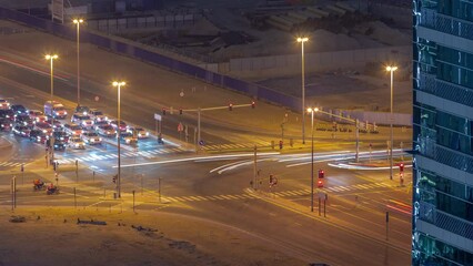 Wall Mural - Bussy traffic on the road intersection in Dubai business bay district aerial night timelapse, UAE. Construction site is behind. Many cars and buses moving on crossroad, UAE