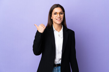 Sticker - Business woman isolated on purple background pointing to the side to present a product