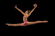 Dynamic portrait of young professional rhythmic gymnastics artist training with ball isolated on black background. Concept of sport, action, aspiration