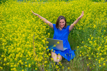 a woman in yellow flowers in a blue dress works on a laptop