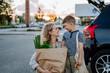 © Halfpoint - Young mother with little son after shopping holding zero waste shopping bags with grocery near car.