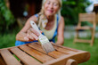 © Halfpoint - Senior woman cleaning and renovating garden furniture and getting the garden ready for summer