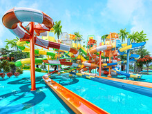 Empty Colorful Waterslides In The Resort Aquapark With Sea View, Sunny Day. Water Slide With Children Pool In Aqua Park, Summer Fun Activity, Vacation Leisure, Holiday Entertainment 3D Illustration