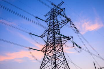 High voltage electric tower at sunset. Transmission power line. Electricity pylons and sky clouds background.