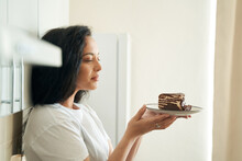 Pleased Woman Seated In Kitchen Looking At Dessert Before Her