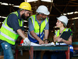 © atitaph - Male and female engineers chat with factory workers as they use machine drawings, planning for industrial maintenance